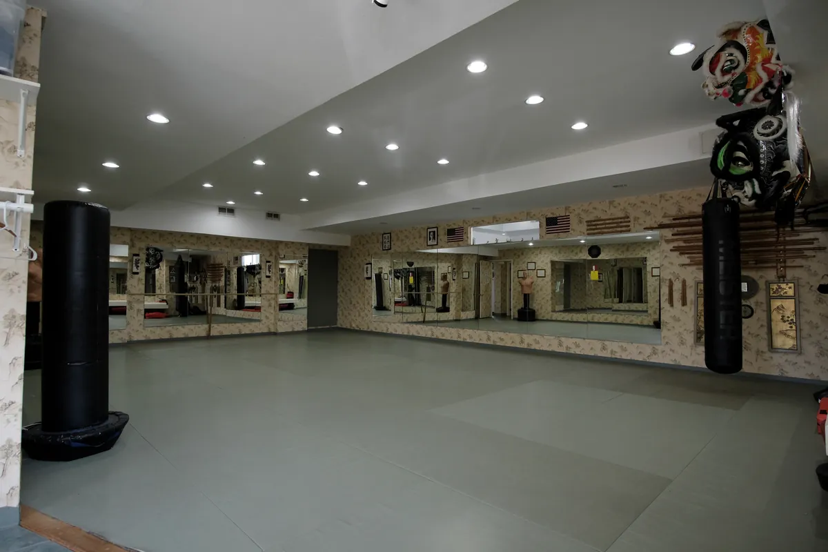 The matted dojo with mirrors and a heavy bag